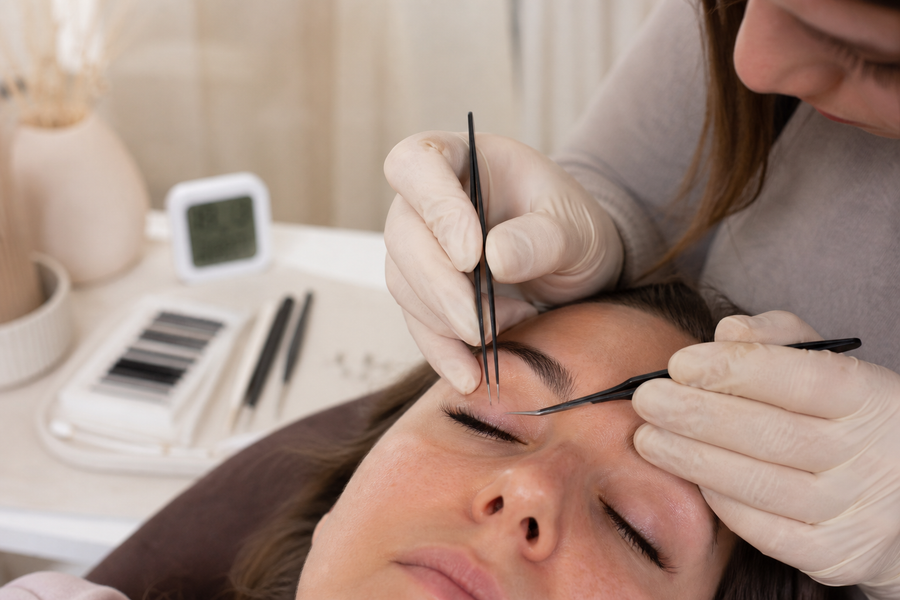 Lash artist inspecting a client’s eyelash extensions during a retention troubleshooting appointment.